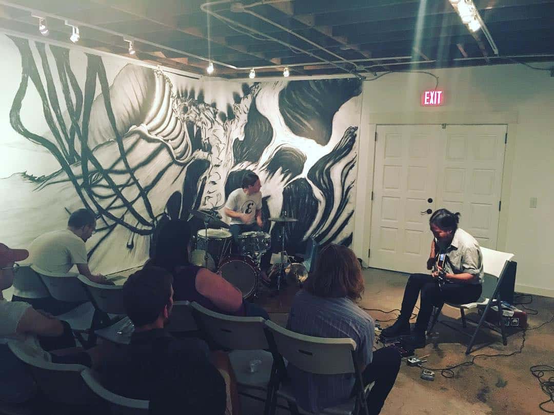 Musicians Tyler Damon (left) and Tashi Dorji playing at ALL in September 2017, in front of a mural by Brianna Lynn Hernandez Baurichter.