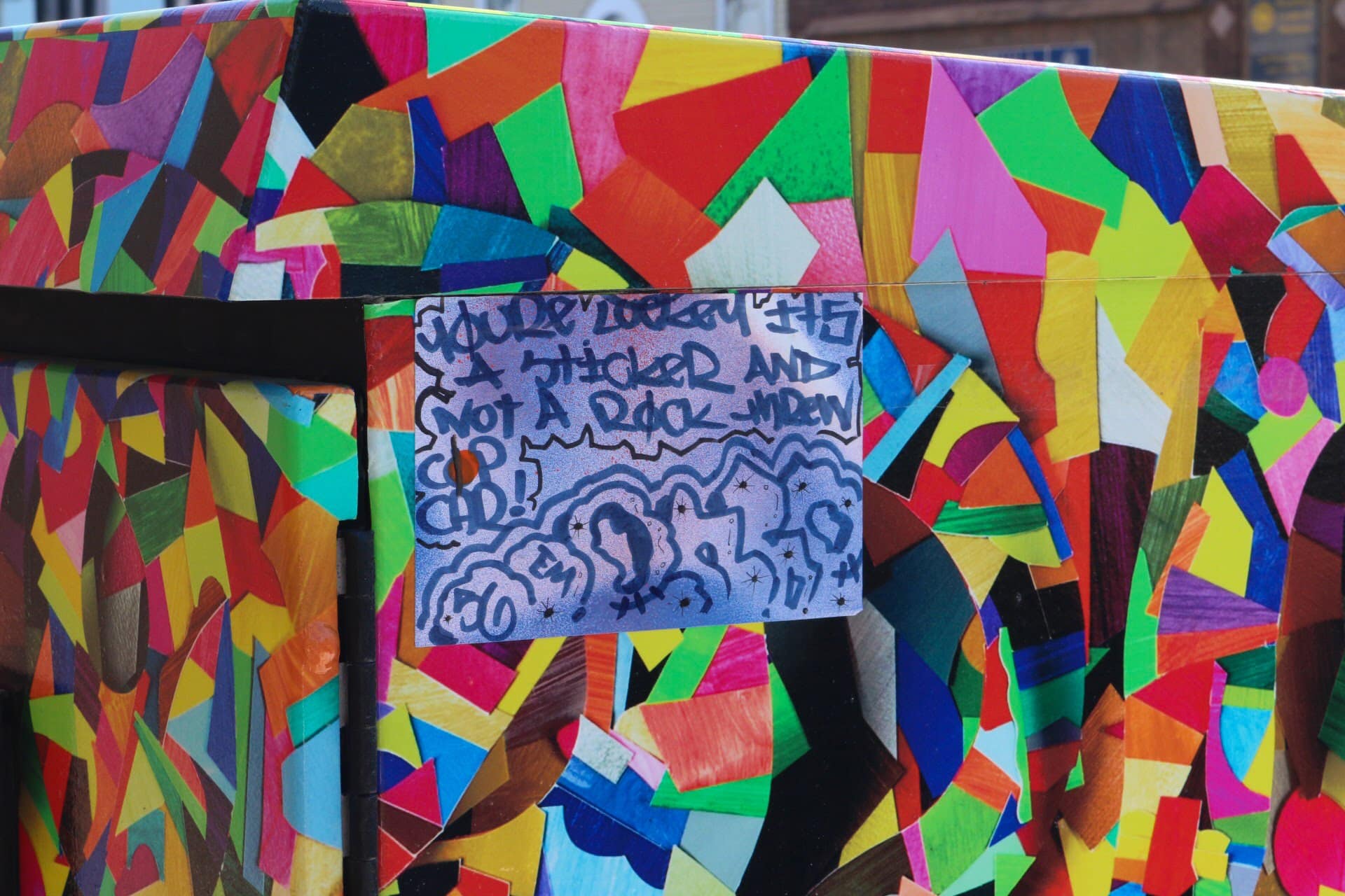 A utility box on Williamson Street features city-sanctioned art by Michael Velliquette, topped with some non-sanctioned street art. 