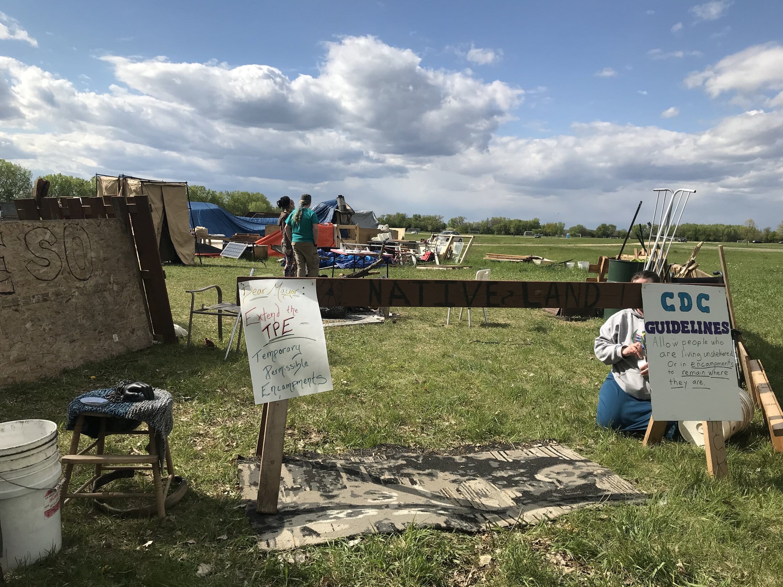 Two homemade signs are stapled at either end of a wooden sawhorse with the words 