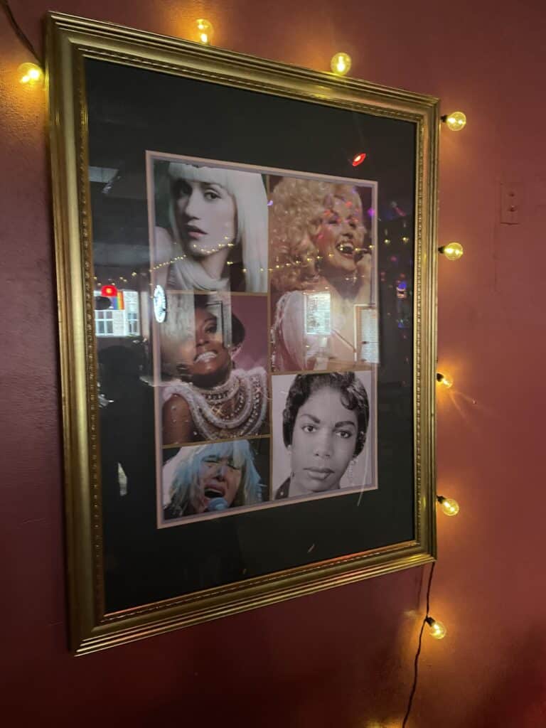 A framed collage on the wall of Mom's Bar shows photos of Gwen Stefani, Dolly Parton, Diana Ross, Nina Simone, and Karen O.