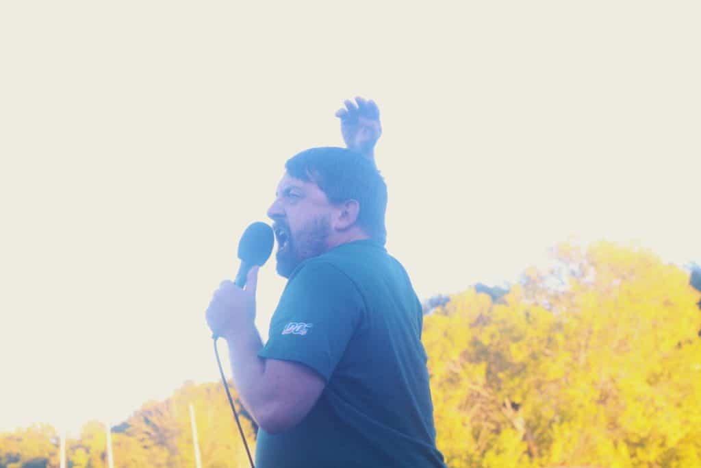 Holy Shit! vocalist Tab Man is shown raising his right hand and screaming into the mic during the second annual Yoop! Festival at the Houghton Skatepark in Houghton, MI.
