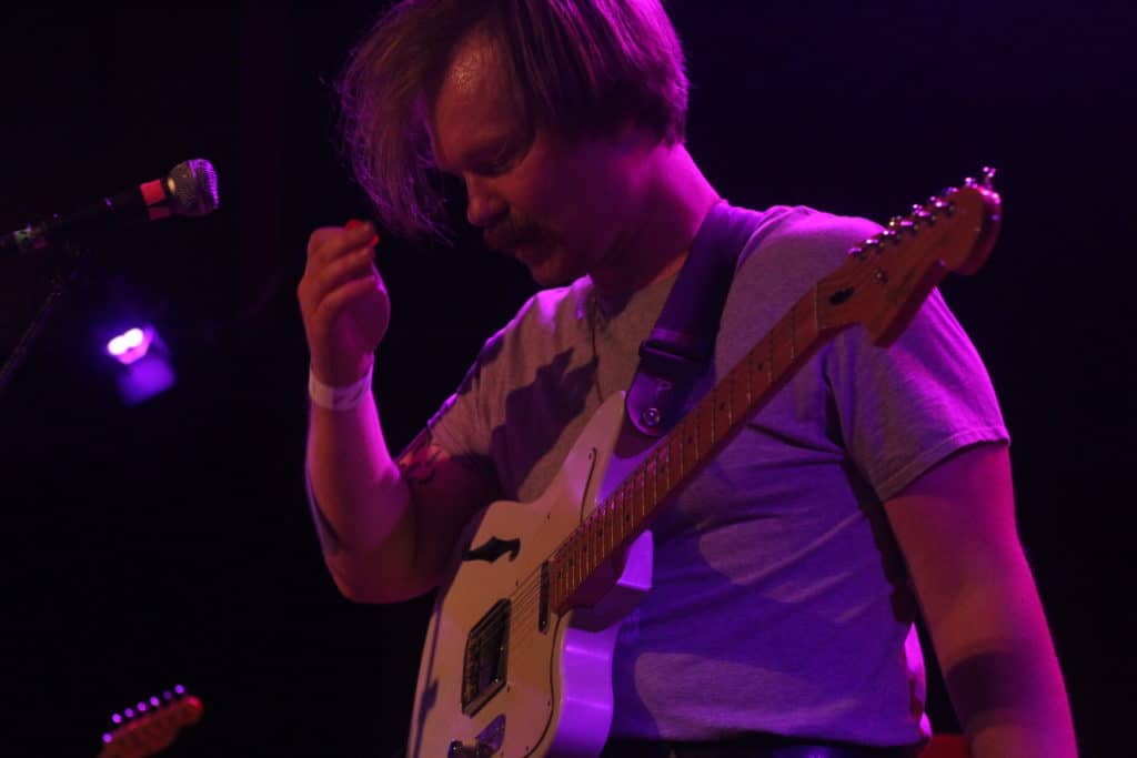 Tyler Fassnacht raises his hand near his head to brush his hair away from his face at the Dirtnap Super Show Extravaganza during Proud Parents' set.