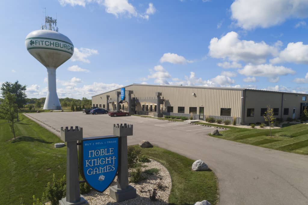 Exterior view of of Noble Knight Games, a large commercial building with castle-themed signs. 