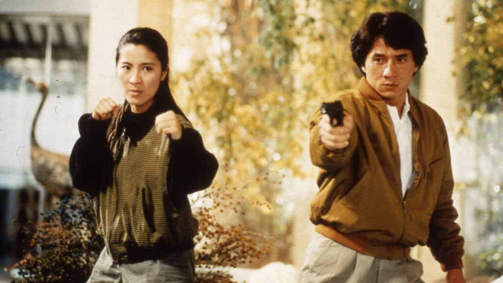 Inspectors Jessica Yang (Michelle Yeoh) and Chan Ka Kui (Jackie Chan) stand side by side with fists and a gun at the ready.