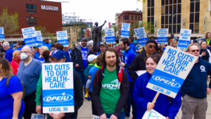 Photo of a crowd of people holding an assortment of OPEIU Local 39 signs with slogans such as "Less than inflation is a pay cut" and "Job security now."