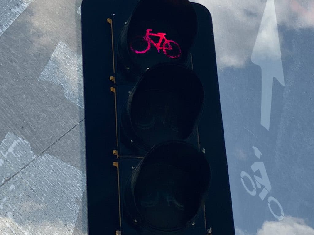 An illustration shows photos of car lane markings, bike lane markings, and a traffic light with bike shapes in it.