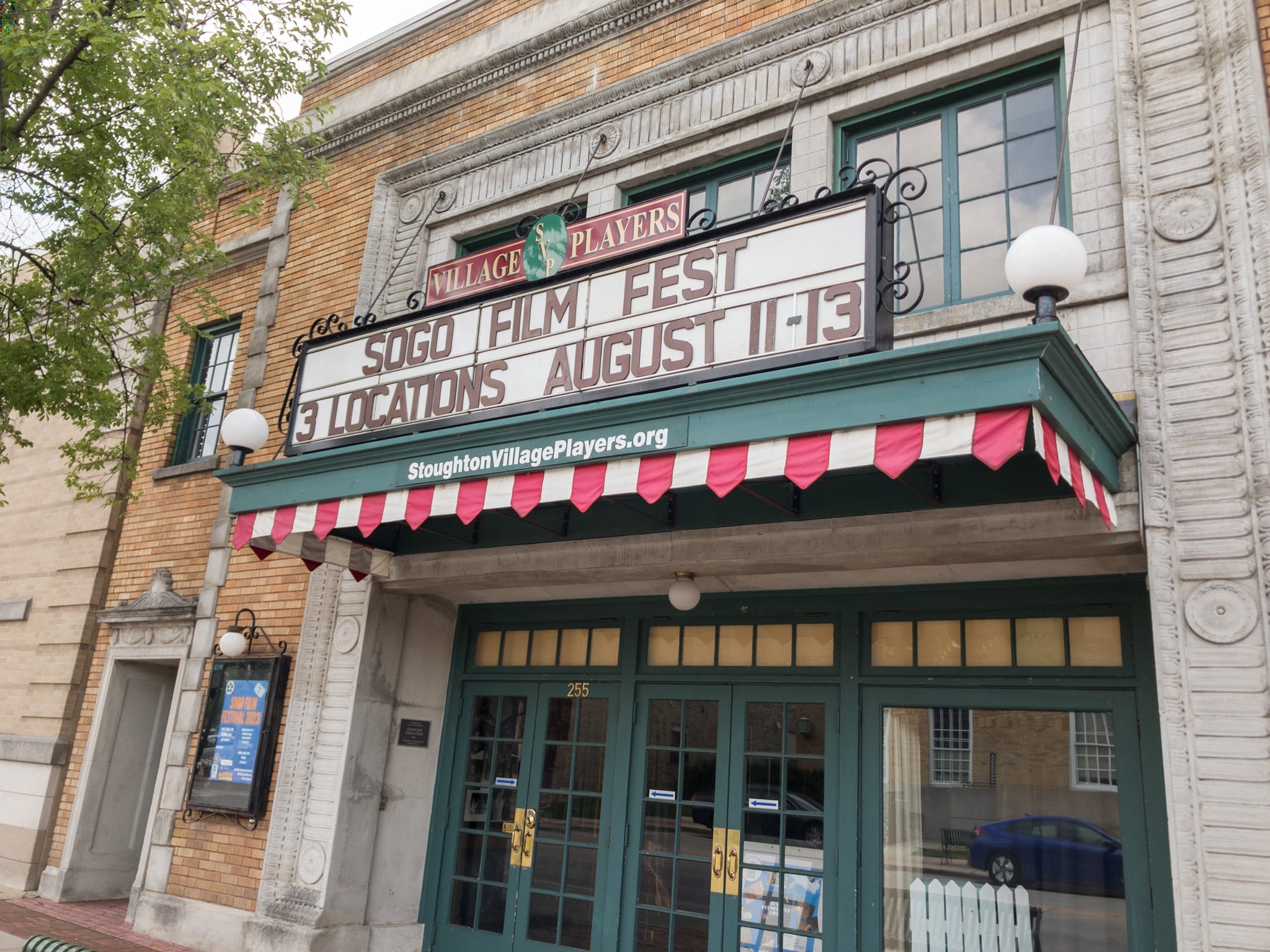 A white marquee with black lettering above a green awning reads "Village Players SOGO Film Fest 3 Locations August 11-13."