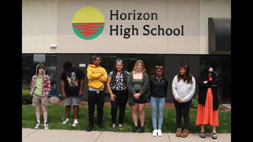 A photographic slide from Kelley and Garver's "Horizon Revealed" captures eight students posing outside the walls of their high school.