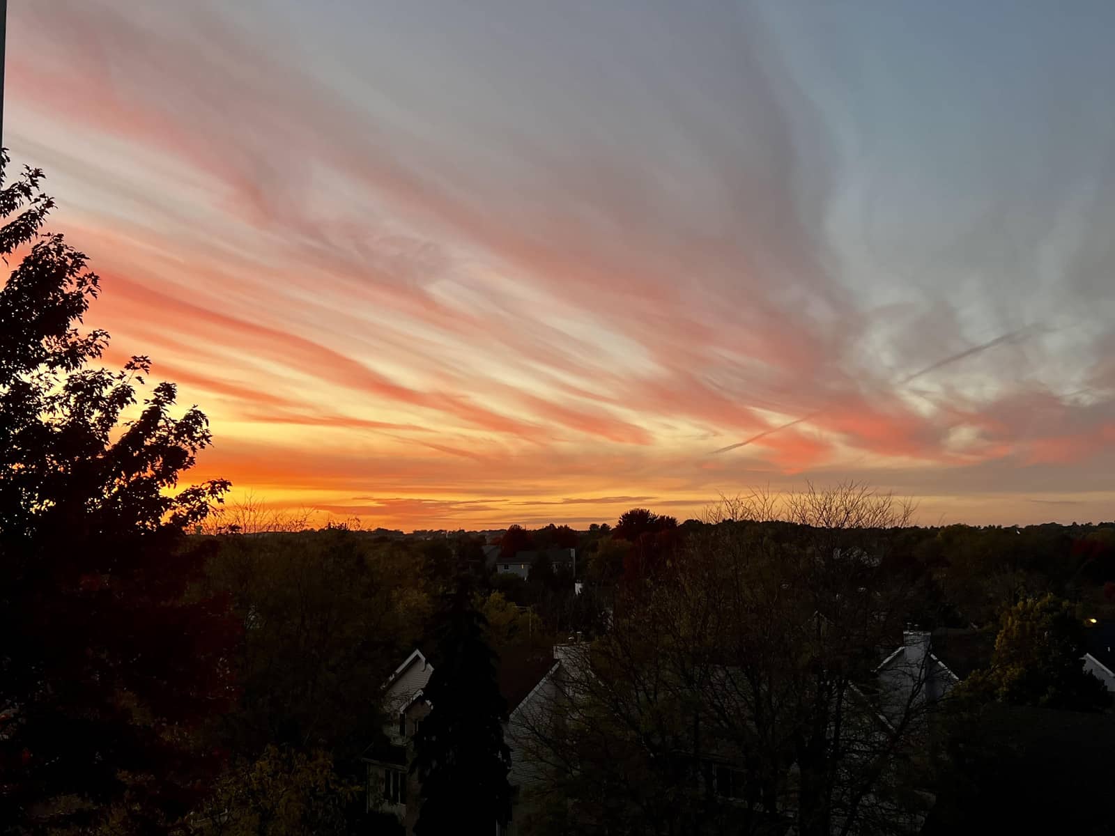 A photograph captured at dusk shows a pretty yellow-orange swirl of colors blending into a dull blue-ish sky above a row of houses.