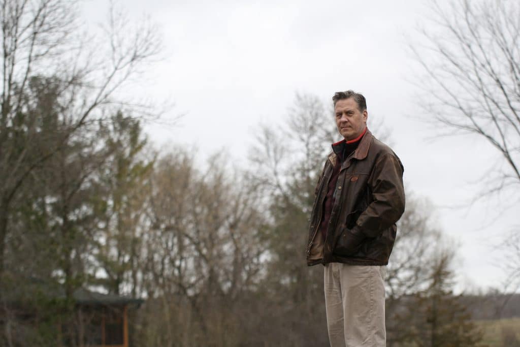 Any Marshall stands outdoors with trees in the background.
