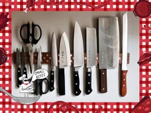 A photo shows an assortment of large and small kitchen knives, and scissors, hanging on a magnetic strip on the wall of a home kitchen. An illustrated frame around the photo depicts a checked tablecloth pattern with various items of food. In the bottom left corner, a small caricature chef stands on a spoon with the speech bubble, "Small Bites."