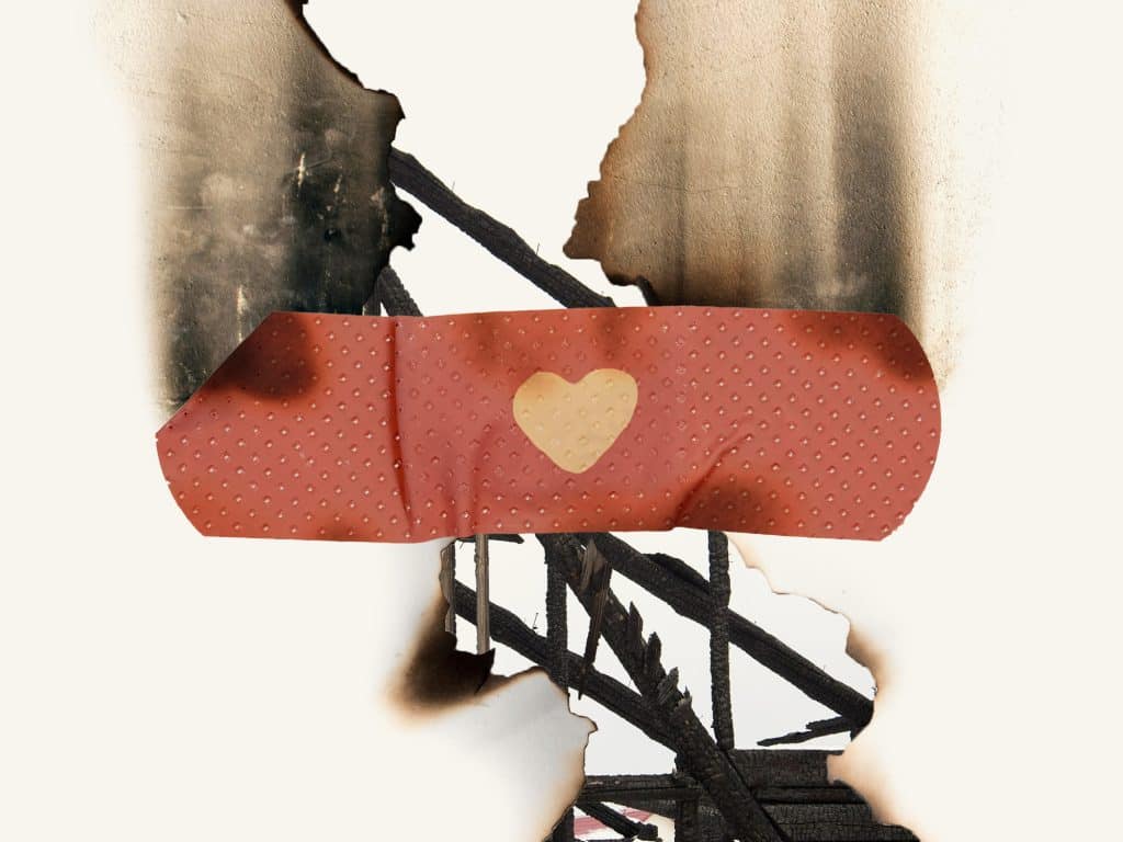 An abstract illustration shows a gap in between two ragged, burnt pieces of paper that also suggest the ruined walls of a building after a fire. In the gap, abstract lines suggesting metal struts can be seen. A bright red bandage, decorated with a heart, spans across the gap.