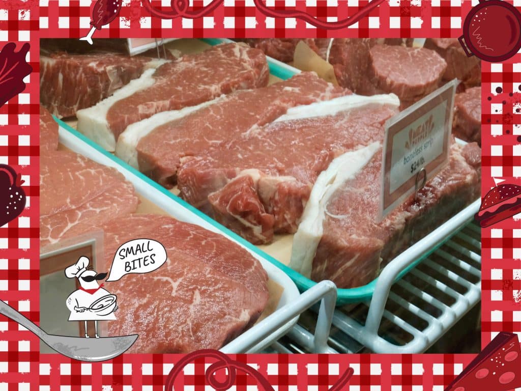 Photo of cuts of meat in a display case. An illustrated tablecloth with food items including pasta, cheese, a hamburger and more frame the photo. In the lower left corner a drawn small chef in a spoon says “Small Bites.”