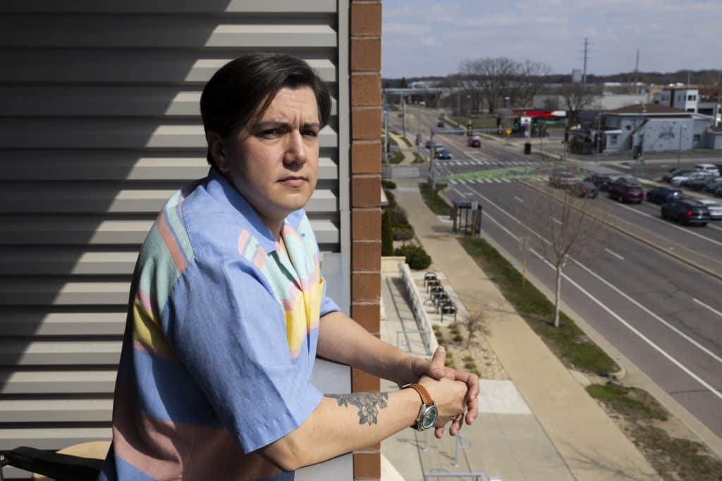 A photo shows a man posing outside on balcony overlooking a street.