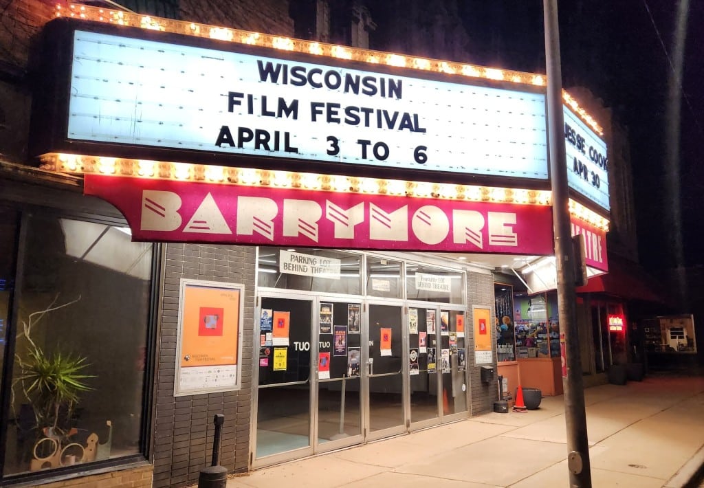 Slightly angled photo at night of the bright, fluorescent-lit marquee at the Barrymore Theatre on Atwood Avenue in Madison, Wisconsin. It reads 