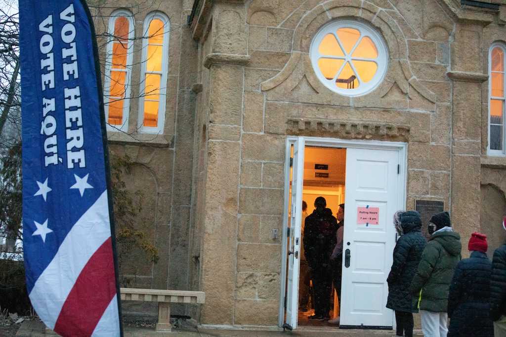 Voters line up outside the Gates of Heaven in Madison with a "Vote Here" sign out front.|A pie graph showing that the biggest reason for election fraud prosecutions was that a voter was under probation.|A table showing the number of election fraud cases by county from 2012 to 2022.|A line graph shows the fluctuations in election fraud prosecutions by year|