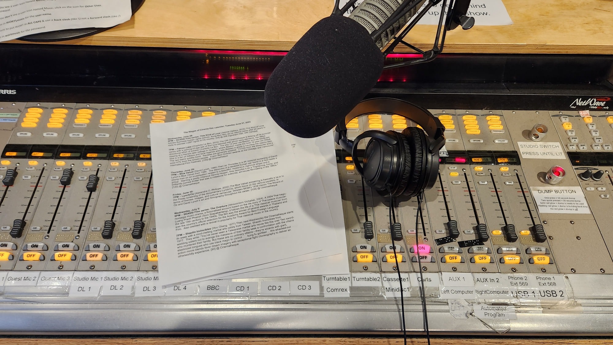 A photo of the mixing console in one of the main WORT studios. JoAnne Pow!ers' "Wages Of Cinema" notes from June 27 and a pair of headphones rest on top of it. The host mic is angled down on the boom arm in the center of the photo.